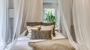 Una cama con dosel, almohadas estampadas y una manta tejida.