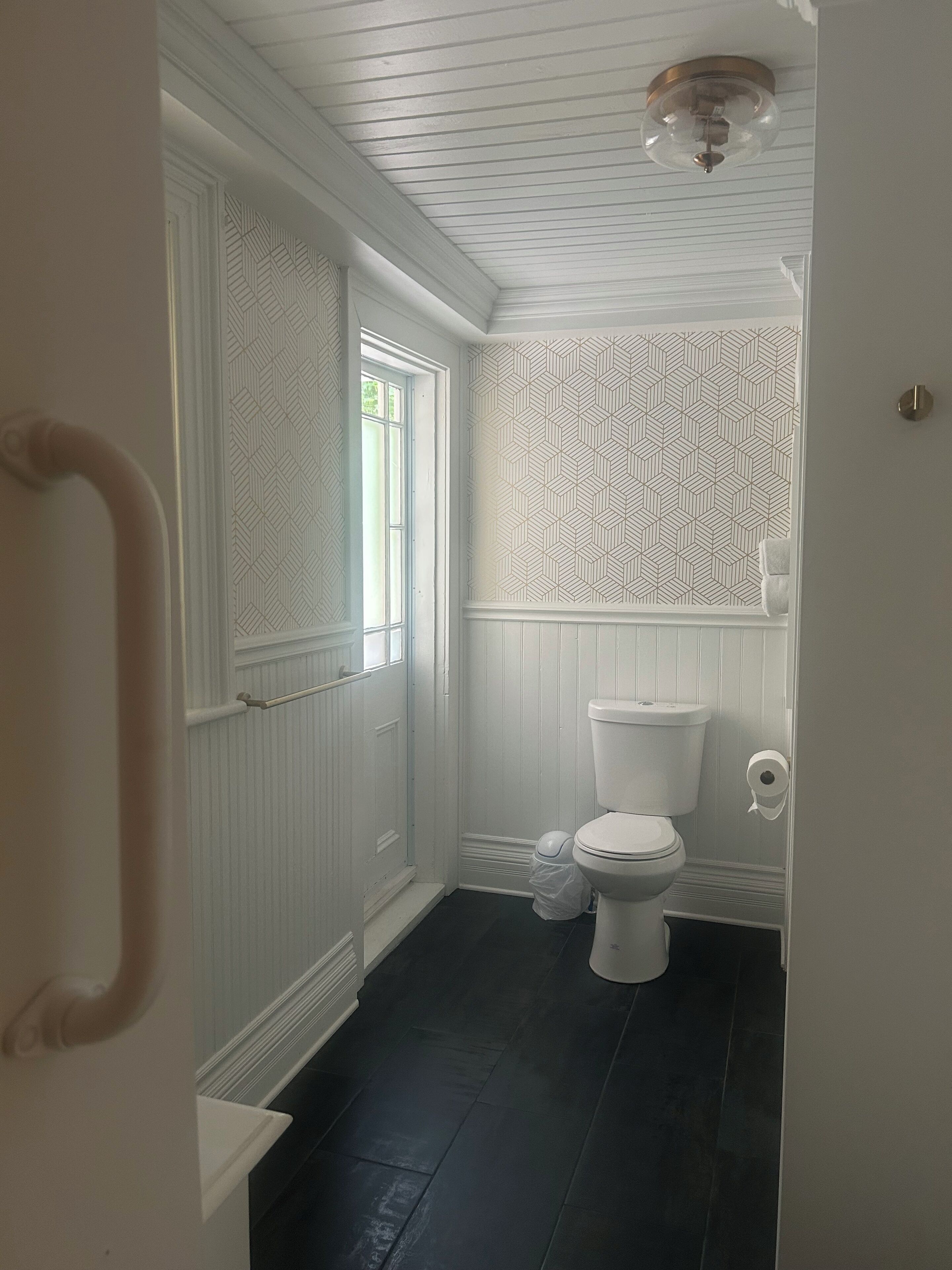 A bathroom with a white toilet, a shower, and a window.