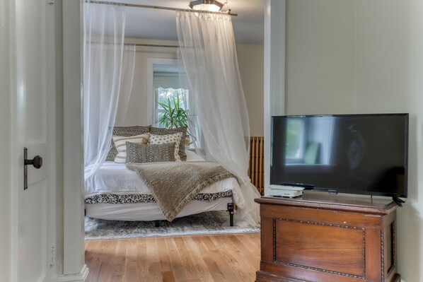 A bedroom with a bed, a TV, and a wooden cabinet.