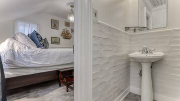Une chambre à coucher avec un lit, une table de chevet, une commode et une fenêtre avec des rideaux.
