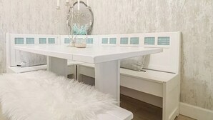 Een witte bank met een zachte witte kussen, een witte tafel met teal betegelde panelen en een decoratieve spiegel met een witte lijst.