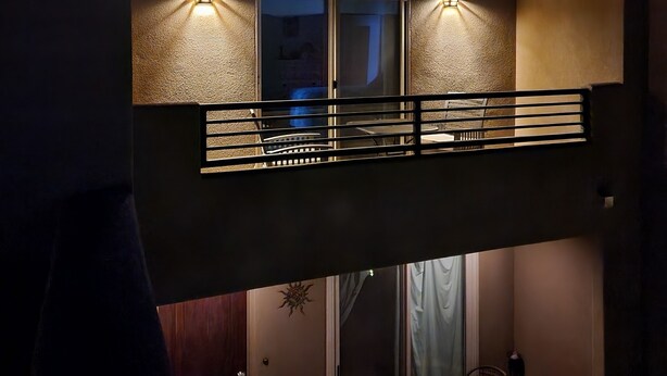 Een gebouw met een balkon, een raam en twee wandlampen.
