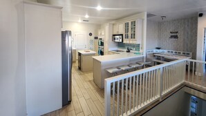 Een moderne keuken met witte kastjes, een koelkast van roestvrij staal en een centraal eiland met zitplaatsen.