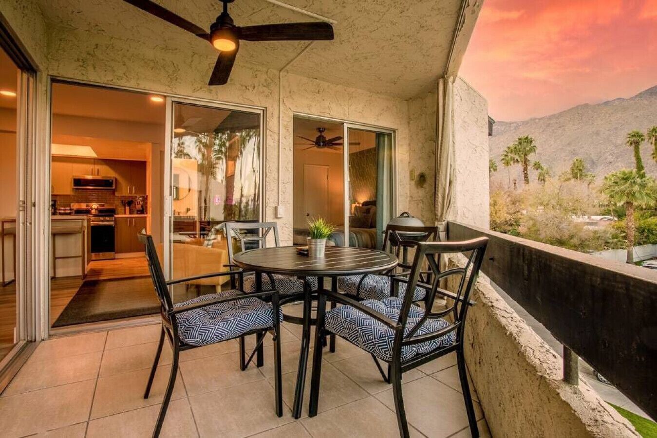 A patio with a round table and chairs, a ceiling fan, and a view of a mountainous landscape.