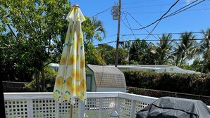 Una terraza techada al aire libre con una mesa, sillas, una parrilla y un farol.