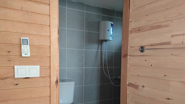 A wooden-paneled bathroom with a toilet, a hand dryer, and a control panel. - Karabibik Bungalow (Demre)
