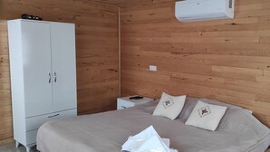 A bedroom with a bed, pillows, a wardrobe, a bedside table, and an air conditioner. - Karabibik Bungalow (Demre)