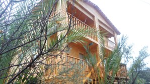 A multi-story wooden building with balconies, surrounded by dense foliage. - Karabibik Bungalow (Demre)