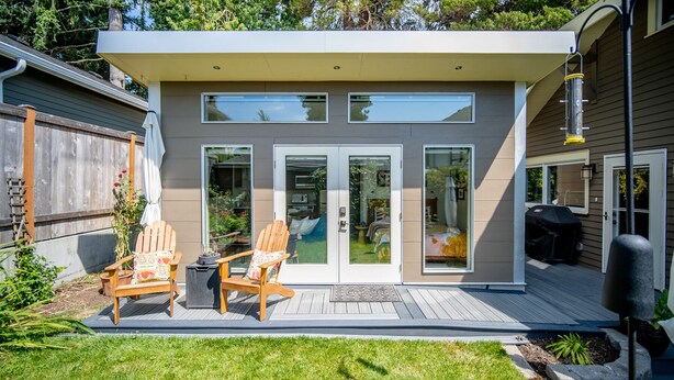 Une maison moderne dotée d’un patio comprenant deux chaises en bois et une petite table.