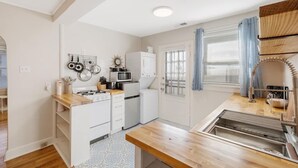 A compact kitchen with a gas stove, microwave, and white cabinets. - 70's Boho 1 BR Near Zoo/Liberty Bowl/BBQ Fest!! (Memphis)