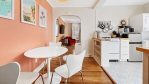 A modern kitchen with white appliances, a dining area with a white table and chairs, and a hallway leading to another room. - 70's Boho 1 BR Near Zoo/Liberty Bowl/BBQ Fest!! (Memphis)