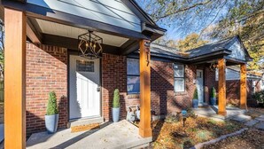 A brick house with a front porch, a door, and a small garden area with potted plants. - 70's Boho 1 BR Near Zoo/Liberty Bowl/BBQ Fest!! (Memphis)
