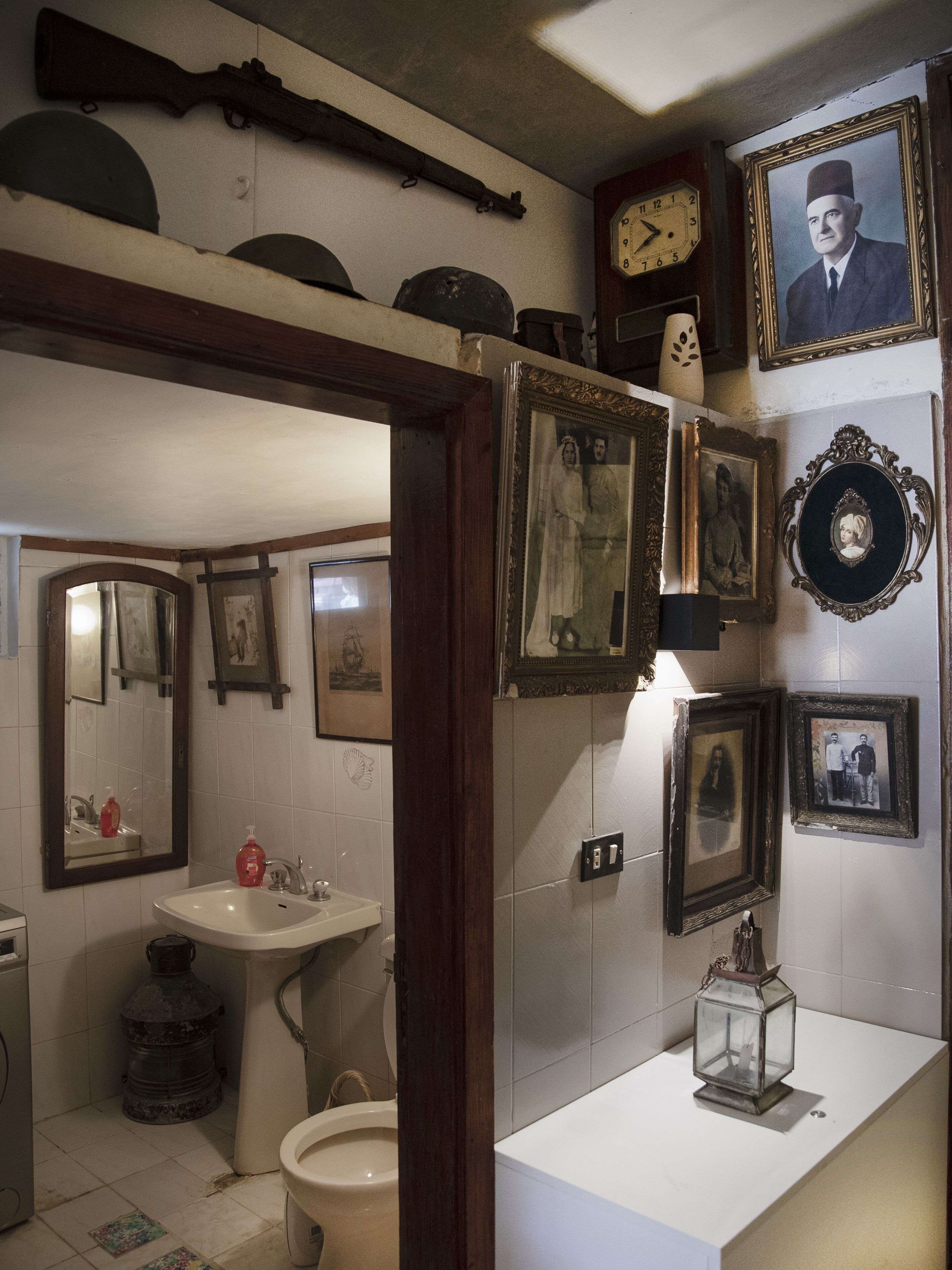 A bathroom with a sink, mirror, and a clock on the wall.