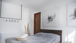 A modern bedroom with a bed, a bedside table, a chair, and artwork on the walls. - 19th Century Charming Ottoman Historical House   (Mount Lebanon Governorate)