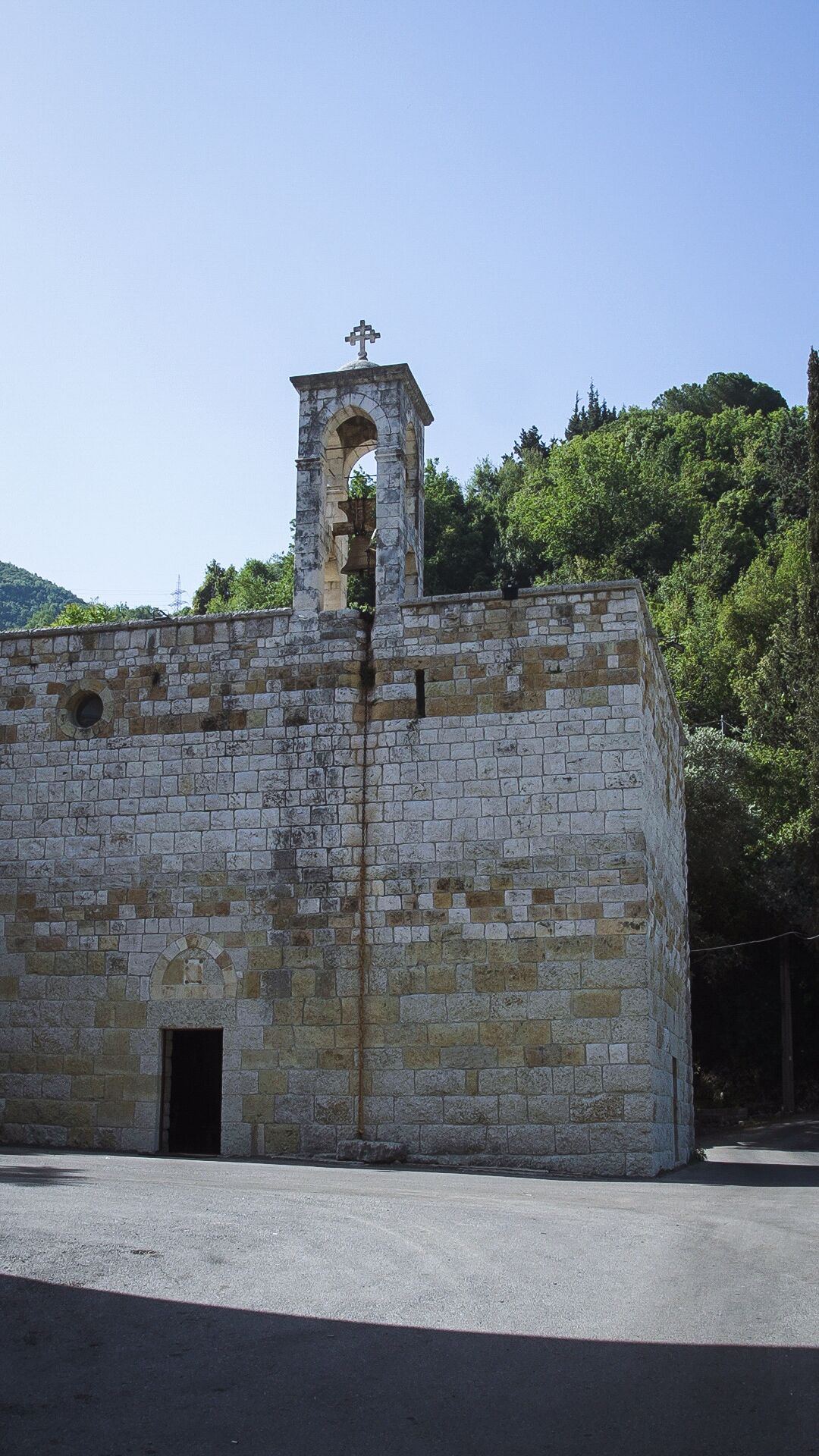 Un edifici de pedra amb una torre campanar, una porta i una petita finestra apuntada.