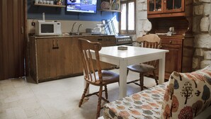 A kitchen with wooden cabinets, a microwave, a stove, and a television. - 19th Century Charming Ottoman Historical House   (Mount Lebanon Governorate)