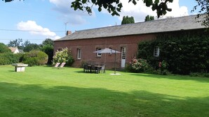 A brick building with a lawn, a table with chairs, and a bench. - 3 Bedroom Private vacation home in ROSAY SUR LIEURE (ROSAY SUR LIEURE)