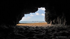 A beach view through a cave opening, with a pier in the distance. - breathtaking sea view Beach FRONT very PRIVATE and quiet SOLAR POWERED (Arecibo)