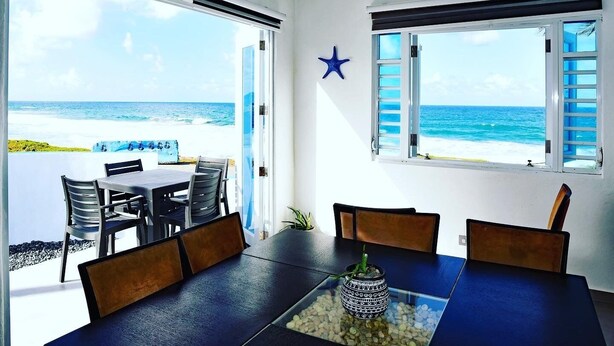 A dining area with a view of the ocean, a star decoration, and a window with shutters. - breathtaking sea view Beach FRONT very PRIVATE and quiet SOLAR POWERED (Arecibo)