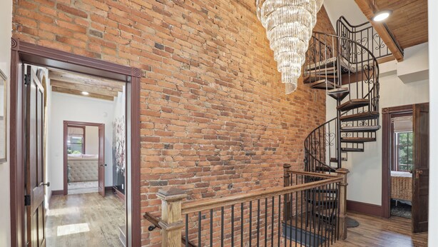 Eine Ziegelwand, eine Holztreppe und eine Chandelüstere.