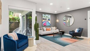 A modern living room with a sofa, a blue armchair, a coffee table, and a cactus plant. - Newly renovated, vibrant and chic Biltmore condo (Palm Springs)