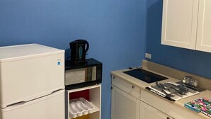 A compact kitchenette with a white refrigerator, a microwave, a coffee maker, and a small sink with a dish rack. - Three Sisters Villa (Mount Thompson)
