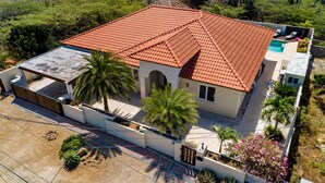 Una casa de dos pisos con techo de tejas rojas, un porche cubierto y una piscina pequeña.