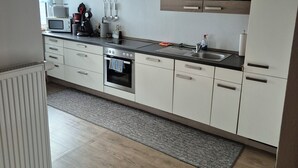 Una cocina moderna con armarios blancos, encimera negra y vigas de madera en el techo.