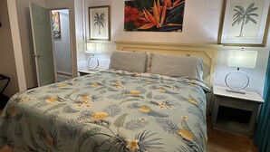Ein Schlafzimmer mit einem Bett, einem Deckenventilator, einem Nachttisch und einer Tür.
