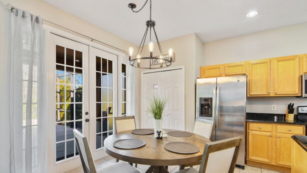 A dining area with a round table, chairs, a chandelier, and a refrigerator. - The Secret Serenity Villa – 3 Miles from Disney, Endless Comfort & Fun (Kissimmee)