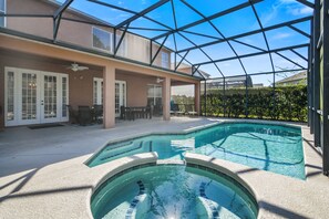 A covered outdoor swimming pool with a patio area, a ceiling fan, and a view of the surrounding landscape. - The Secret Serenity Villa – 3 Miles from Disney, Endless Comfort & Fun (Kissimmee)