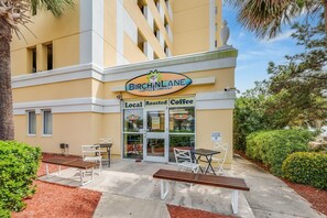 Situated in a modern setting, the Birch Lane Coffee Company offers outdoor seating with white chairs and tables.