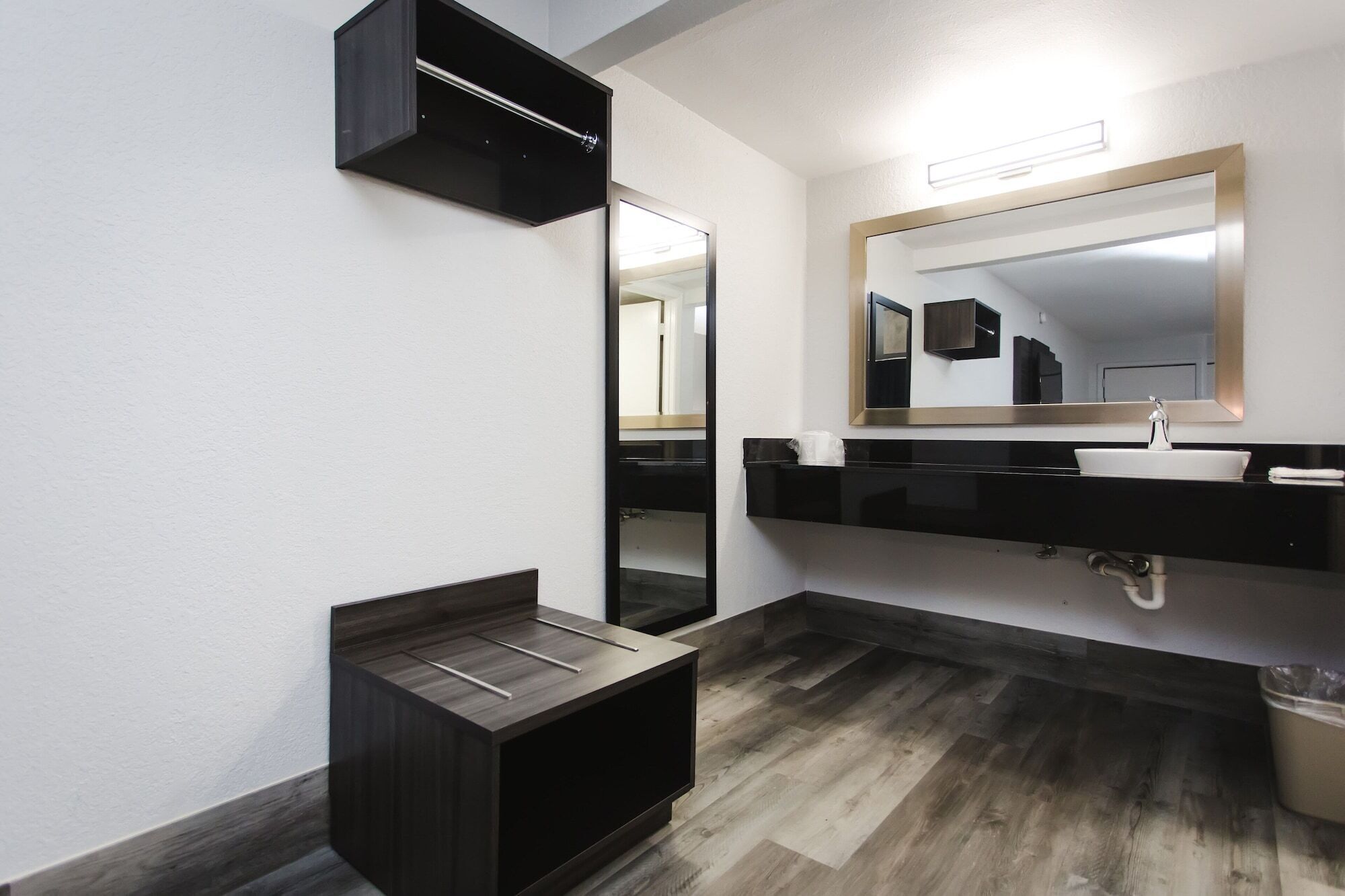 A modern bathroom with a dark wood vanity, a large mirror, and a white sink.