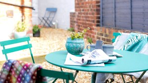 A green table with a vase, a mug, and a magazine. There is a chair with a colorful blanket. - Central Harrogate 2 Bed Victorian Terrace (Harrogate)