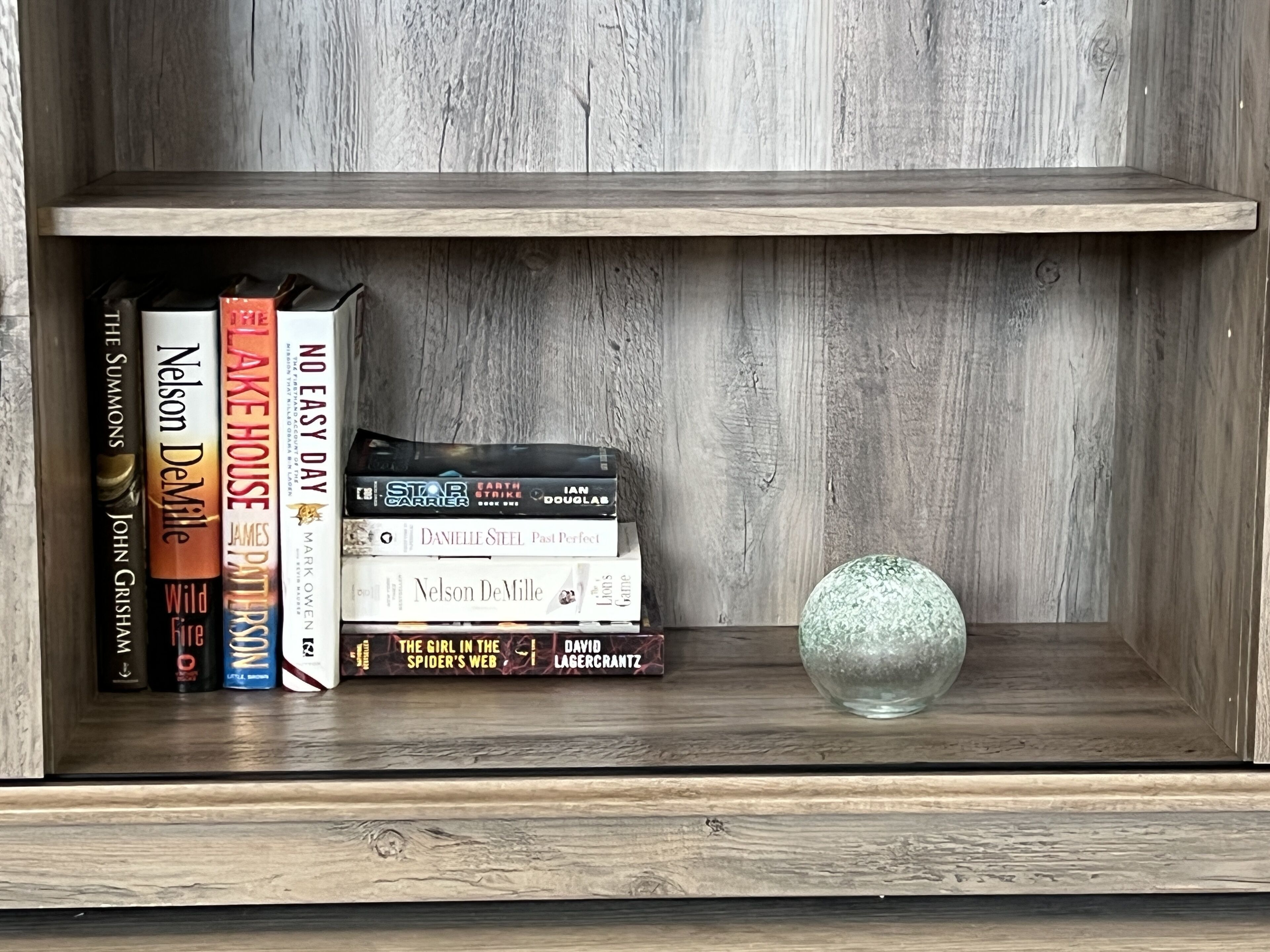 Une bibliothèque en bois, avec des livres et une sphère de verre décorative.