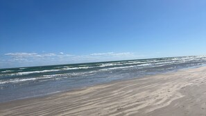 Ein Strand mit breitem Sandufer und sanften Wellen.