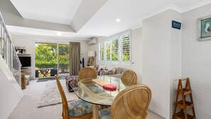 Relax in this stylish living area with a glass-top dining table and comfortable sofa, perfect for unwinding with a view of the lush outdoor space.