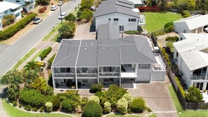 Residential building with a flat roof and balcony, surrounded by well-maintained lawns and gardens.