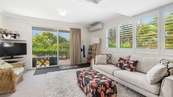 Relax in style with a large flat-screen TV, comfortable sofa, and wicker chairs.