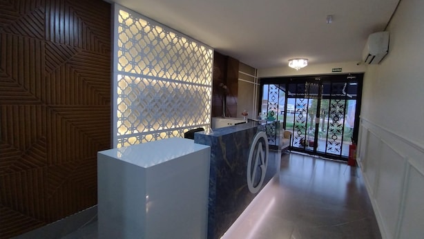 Un área de recepción con mostrador de mármol, pared decorada y vistas al exterior a través de un ventanal.