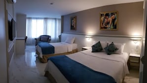 Una habitación de hotel con dos camas, una silla, un escritorio y un cuadro en la pared.