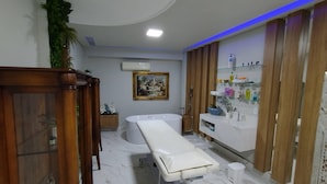 Un baño moderno con una bañera blanca, un mueble de tocador de madera con estantes de vidrio y suelo de mármol.
