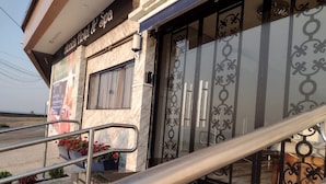 Fachada de hotel de mármol, barandillas de metal y paneles de vidrio decorativos.