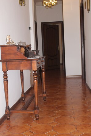 A wooden table with drawers and a decorative item on it, placed in a hallway with hexagonal patterned flooring.