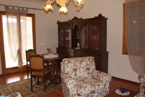 A dining area with a wooden table, chairs, and a floral sofa.