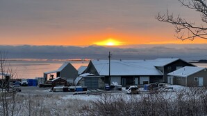 A rural area with a sunset over a body of water, houses, and scattered debris. - Fantastic Beach & Ocean Views (Grand Manan)