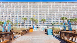 A hotel with a large building facade, a wooden boardwalk leading to the entrance, and surfboards displayed outside. - Beautiful Gulf Front Condo!  Summit 627 (Panama City)