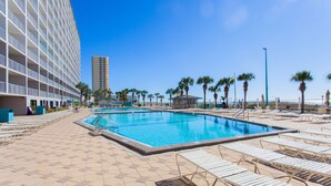 A hotel pool area with a tiled deck, lounge chairs, and a palm tree-lined promenade. - Beautiful Gulf Front Condo!  Summit 627 (Panama City)