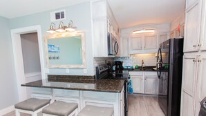 A modern kitchen with white cabinetry, a black refrigerator, and a marble countertop. - Beautiful Gulf Front Condo!  Summit 627 (Panama City)