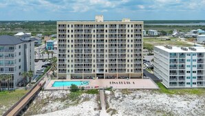 Ein mehrstöckiges Hotel mit Poolbereich, einem Zugang zur Strandpromenade und Blick auf die umliegende Landschaft.